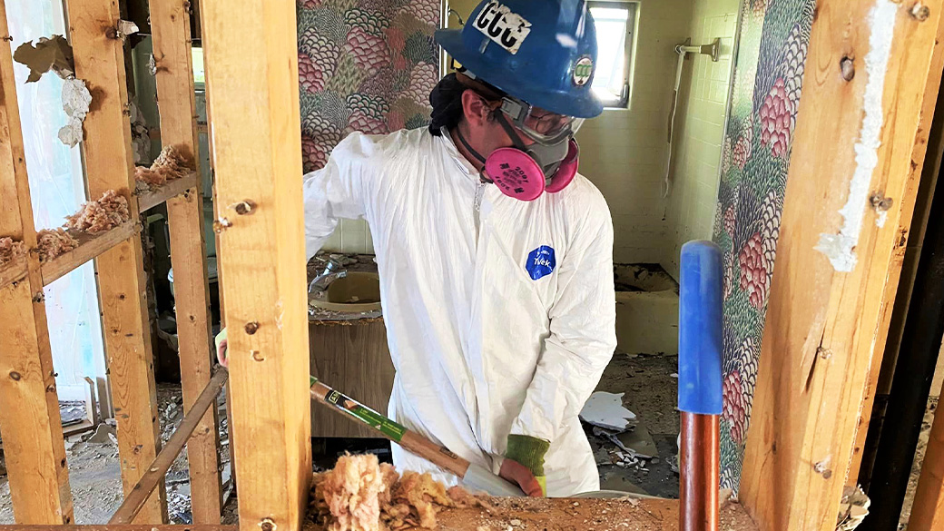 corpsmember wearing respriator working between studs