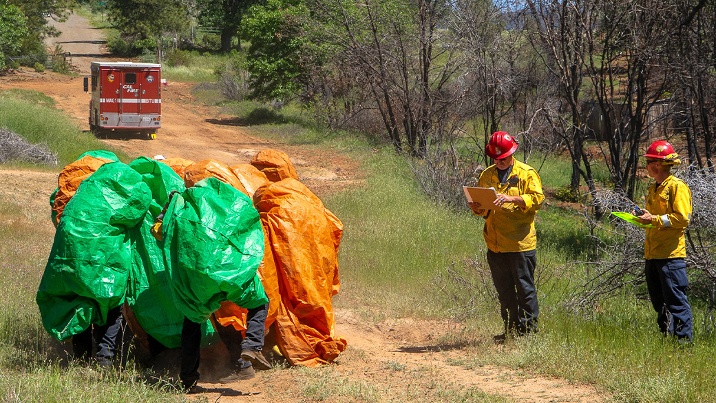 corpsmembers in tarps completing shelter deployment drill
