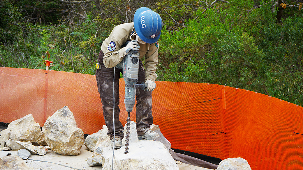 Corpsmember working on trails project, drilling through rock.