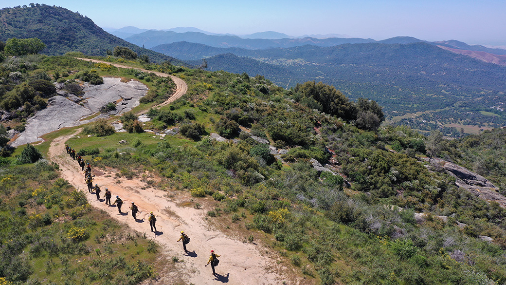 aerial photo of corpsmembers hiking up trail above a valley