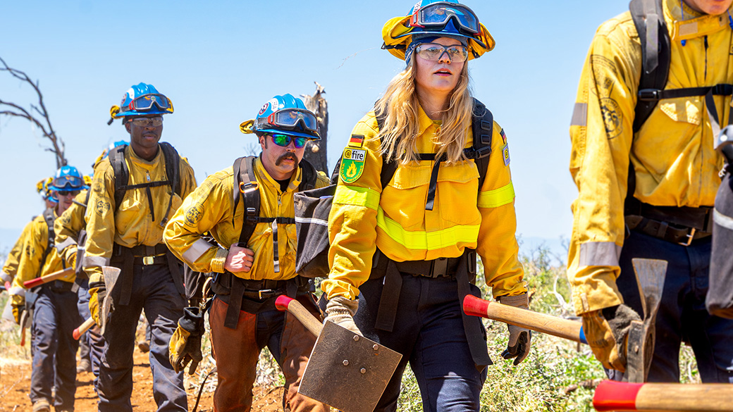 crew of american an german firefighters hike in uniform and with hand tools