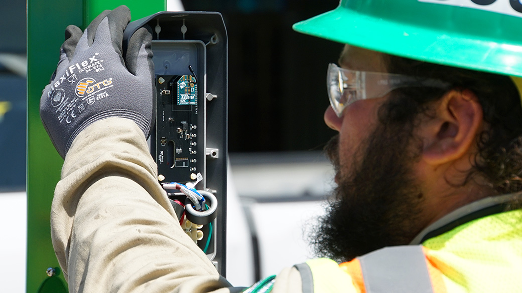 Norwalk_Resource_EVBoxInstall_042925_1040x585 male corpsmembrer holding ev charging box to post