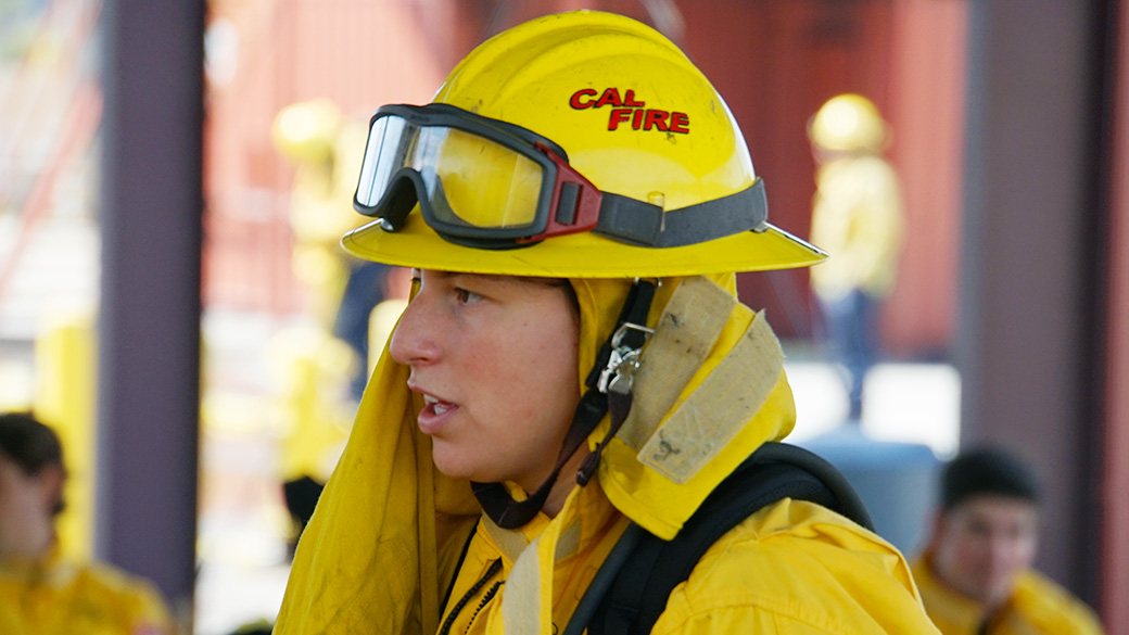 female in full wildland firefighting gear talks to someone off camera