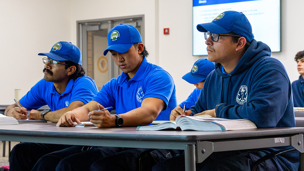 three corpsmembers sitting at a table taking notes