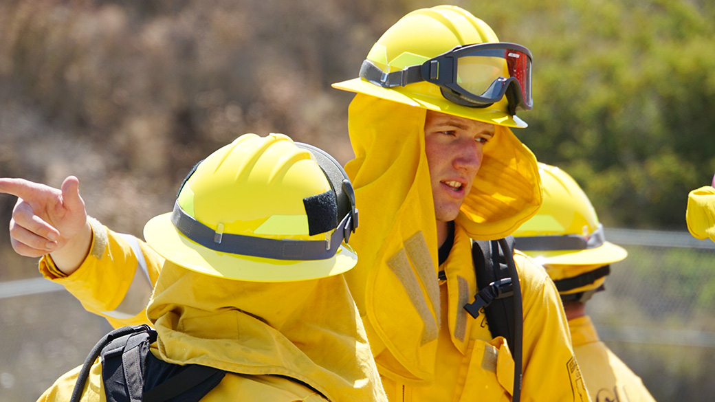 LosPinos_OrientationTraining_SDUHires_062525_1040x585 male in full wildland fire gear points off camera and talks to other firefighters
