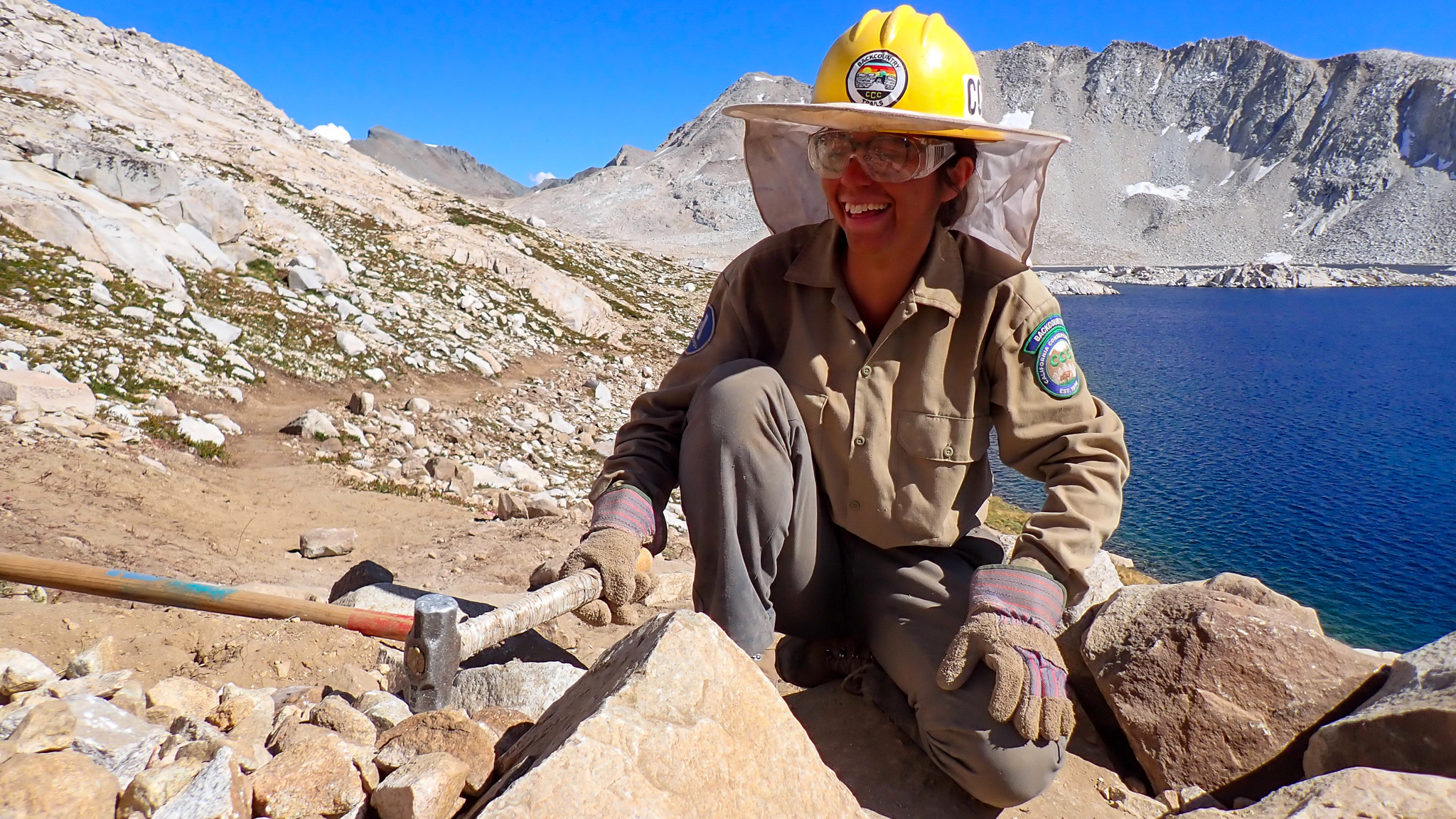 BCTP_MichelleLopezLorenzo_2025_1040x585 female smiles while holding a hammer in front of an alpine lake