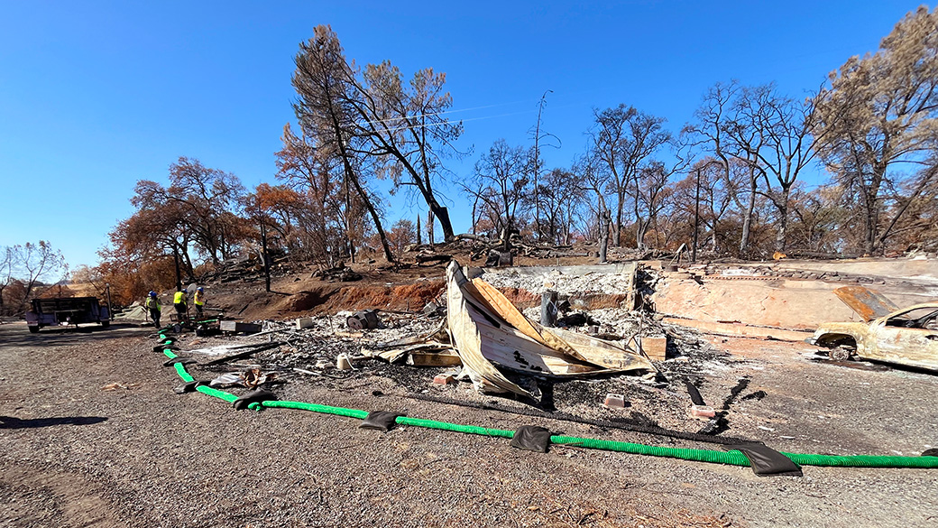 Delta_Emergency_ChineseCampWatershedProtection_101025_1040x585 green silt sock surround a burned home, with corpsmembers working in the far distance