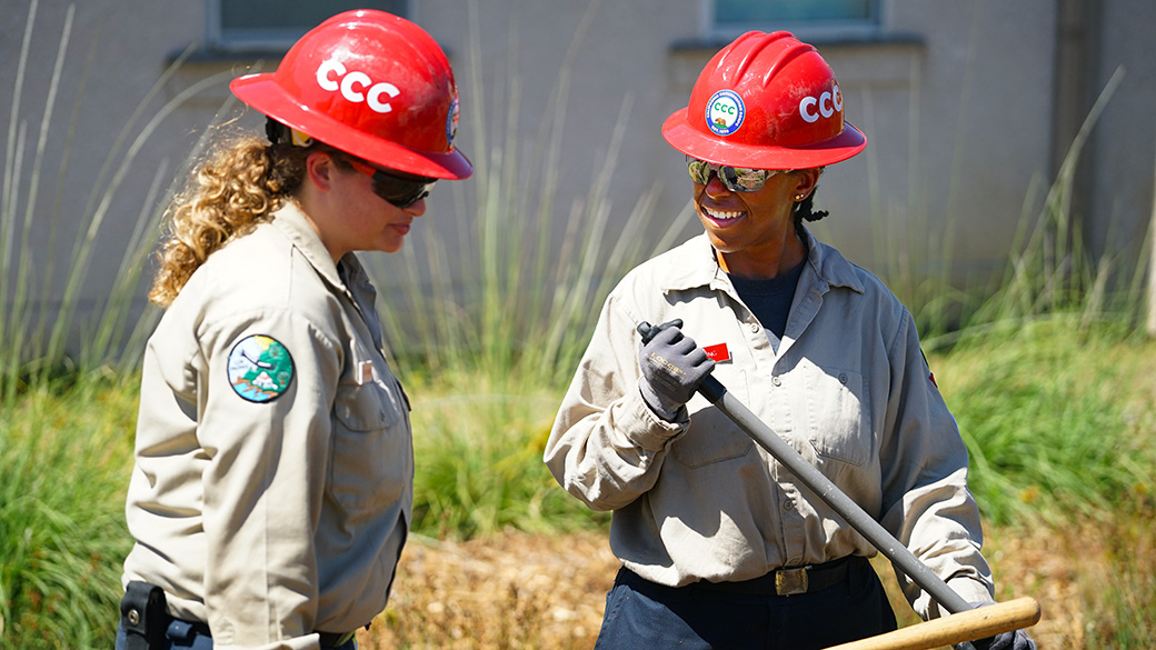 two female corpsmembers in red hats exchange smiles and pleasantries