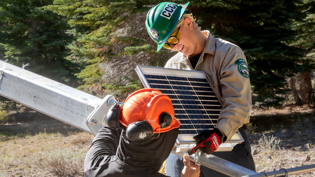 CCC Corpsmember works with DWR consultants to install a solar pannel on a weather station