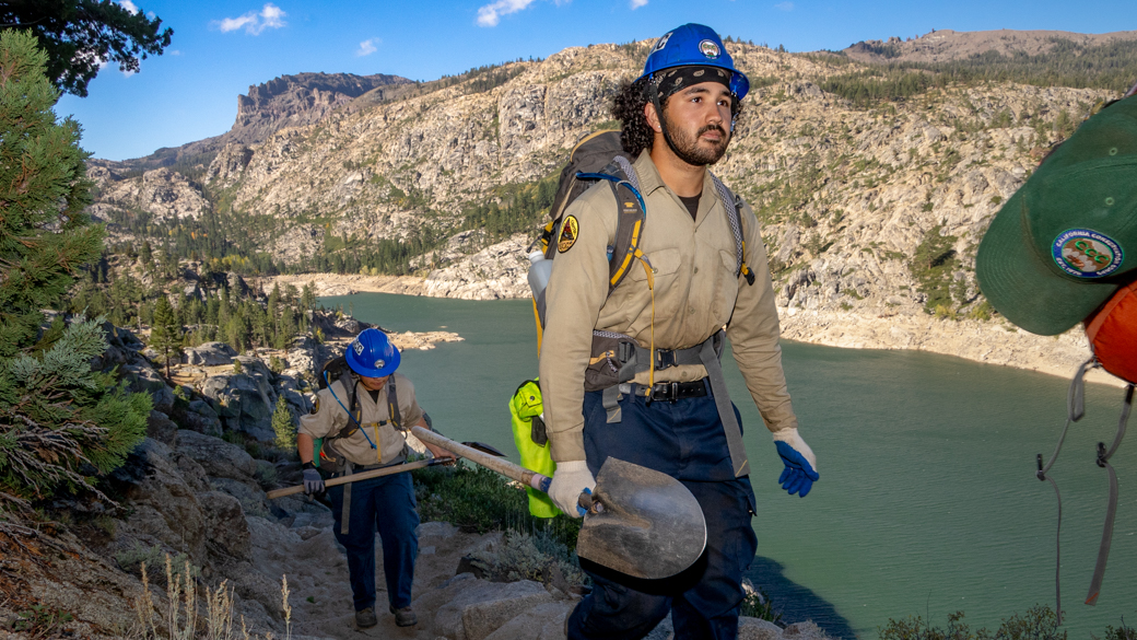 Levai Jimenez hikes past Relief Reservoir with shovel in hand.