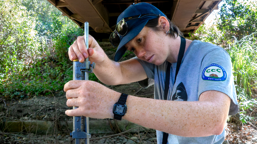 CCC WSP Corpsmember Maeve Gallagher adjusts a USGS top rod - a tool used to measure creek depth.