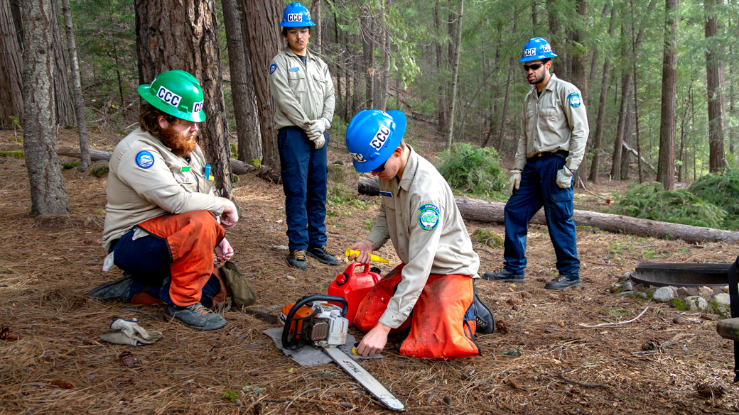 CCC Corpsmembers prep chainsaws in a forest.