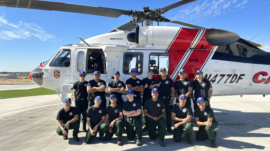 A CCC Crew poses in front of a helicopter.