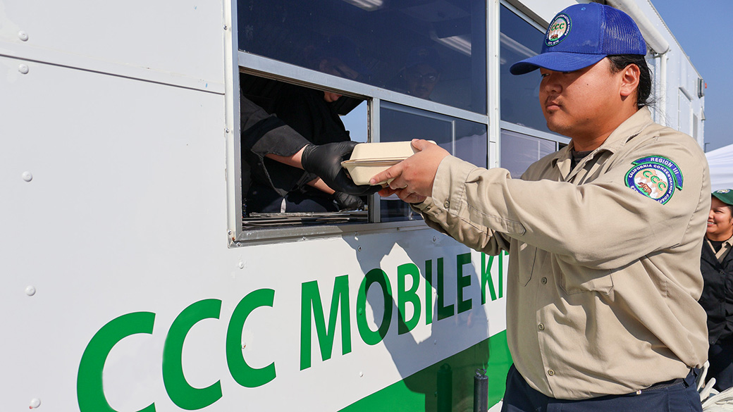 male corpsmember hands box of food in window