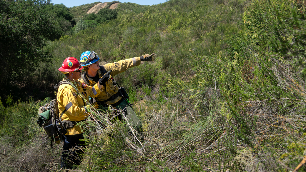 A CCC Corpsmember and CAL FIRE captain communicate as they prepare to cut handline in the Santa Margarita hillside.