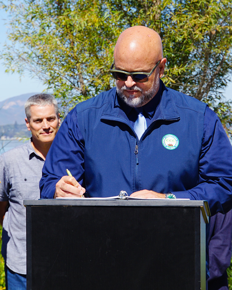 male holding pen and signing with podium